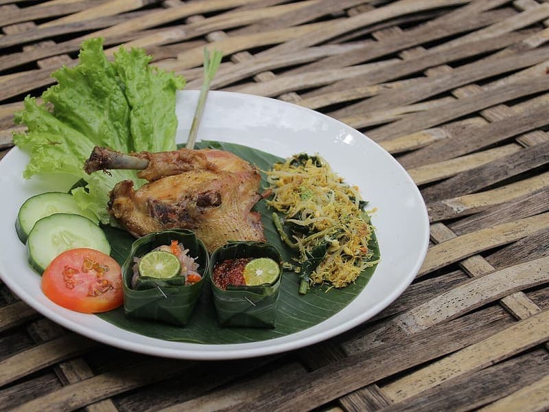 Ayam goreng bumbu kuning dengan sambal matah dalam takir daun pisang dan lalapan segar