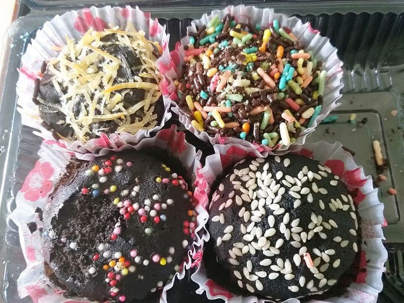Brownies kukus cokelat dengan topping keju, meses, dan wijen dalam kemasan mika