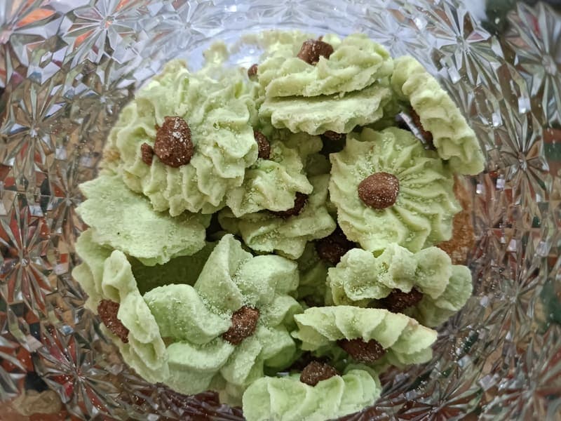 Kue semprit pandan dengan butiran cokelat dalam toples kaca